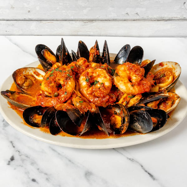 Platter of mussels, clams, and shrimp in a rich tomato sauce, garnished with fresh herbs.