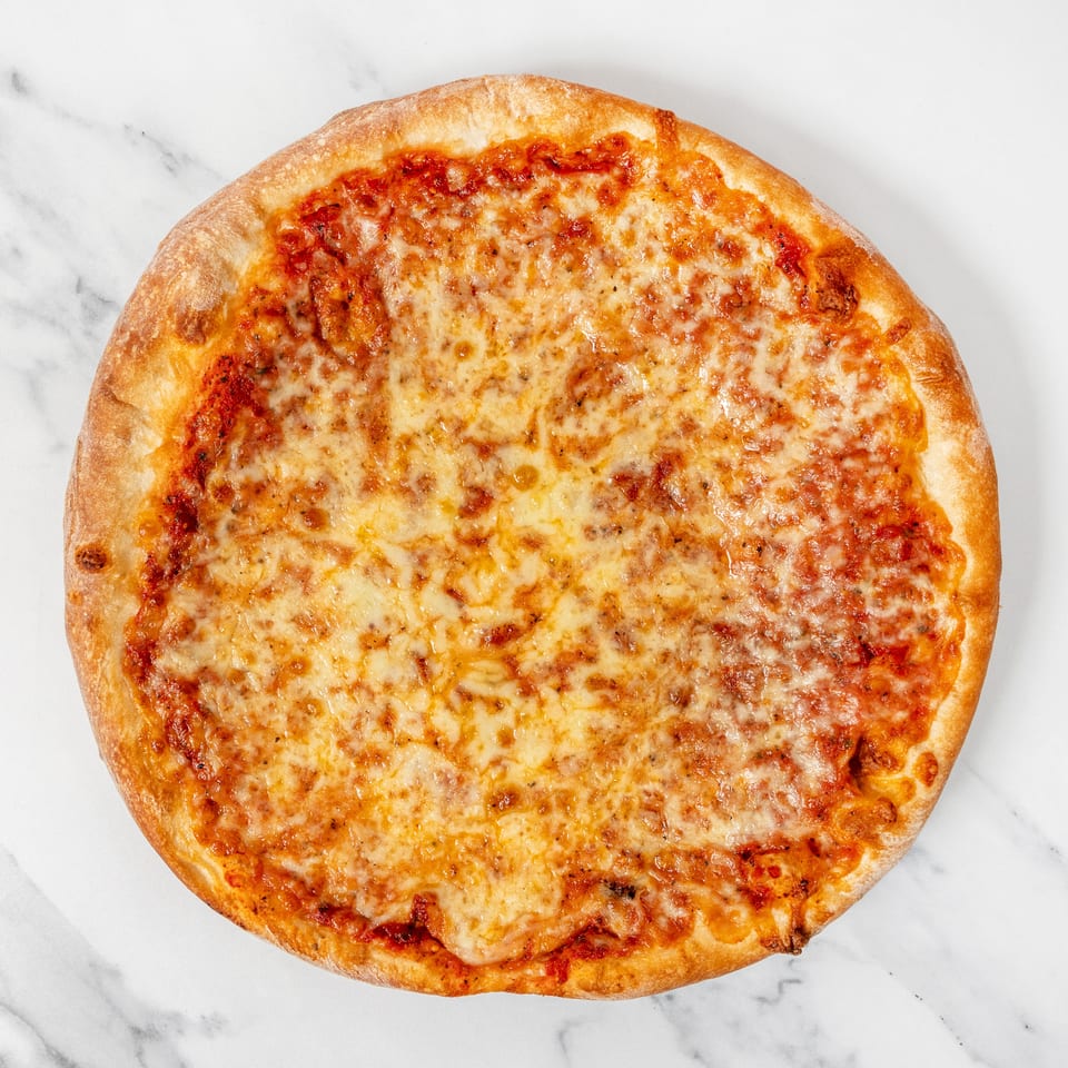 Round cheese pizza with golden crust and melted mozzarella on a white marble surface.