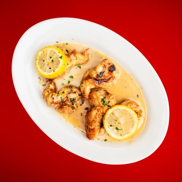 Pan-seared shrimp in a creamy lemon sauce, garnished with parsley, served on a white oval plate.